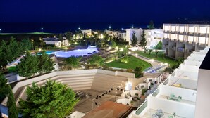 A modern hotel with a pool, outdoor seating, and a view of the sea.