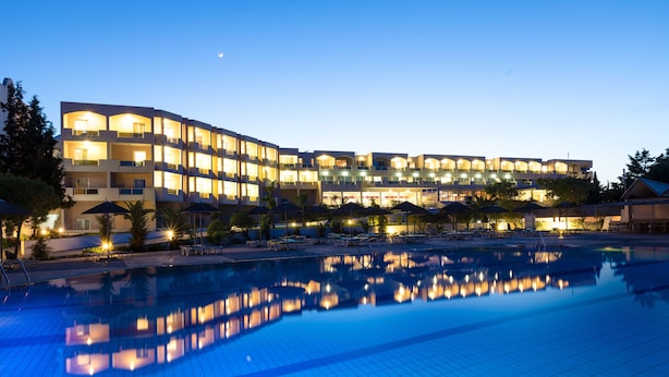 A hotel with a swimming pool, multiple balconies, and outdoor seating areas.
