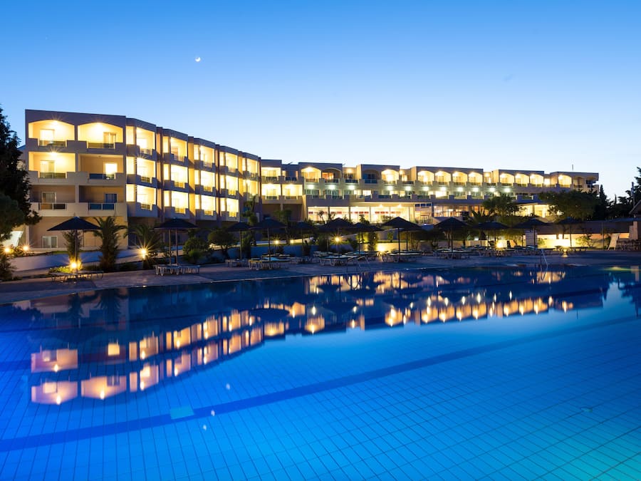Un hotel con piscina, varios balcones y zonas de estar al aire libre.