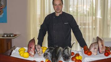 A chef standing behind a table with various seafood and lemons.