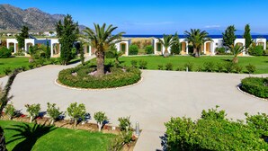 A resort with a central courtyard, palm trees, and a view of the sea.