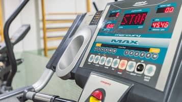A stationary exercise bike with a digital display, control buttons, and an emergency stop button.