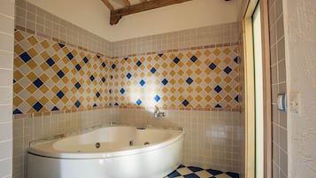 A bathroom with a freestanding bathtub, tiled walls, and a checkered floor.
