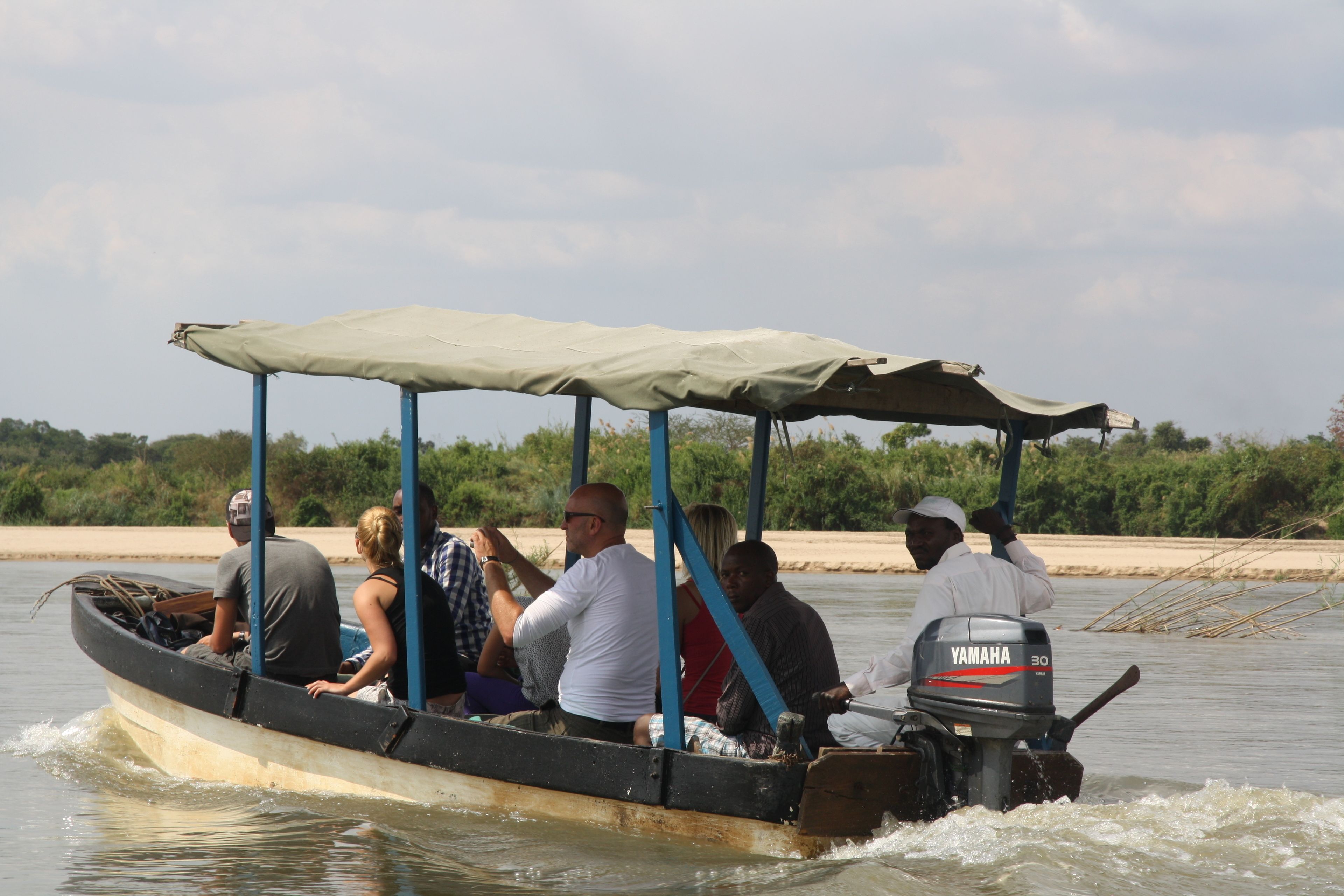 A boat with a canopy and an outboard motor, carrying several passengers.