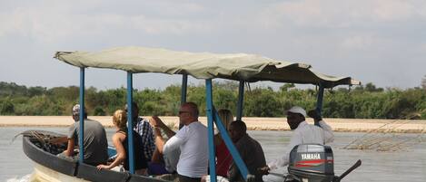 A boat with a canopy and an outboard motor, carrying several passengers.