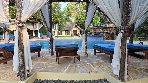 A poolside area with lounge chairs and a wooden bench. - Africa Safari Selous (Selous Game Reserve)