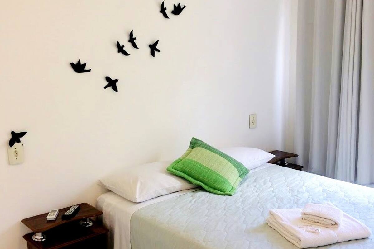 Une chambre d’hôtel avec un lit, des oreillers, une table de chevet et une décoration murale représentant des silhouettes d’oiseaux.