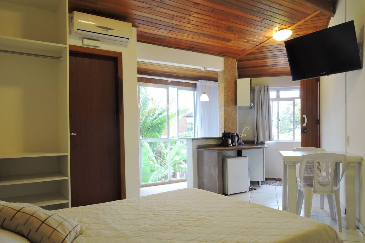 Une chambre comprenant un lit, une armoire, un coin cuisine, un bureau et un téléviseur.