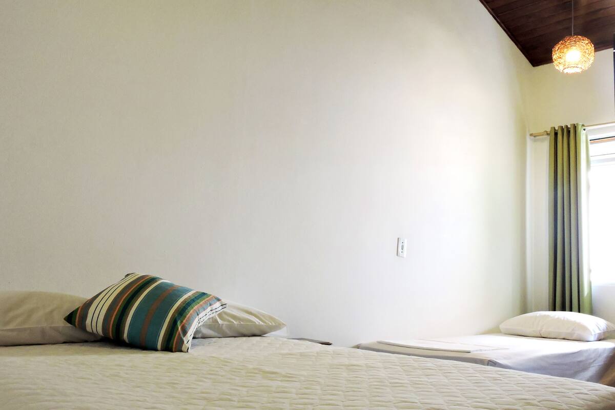 Une chambre avec deux lits, un coussin à rayures et un luminaire suspendu.