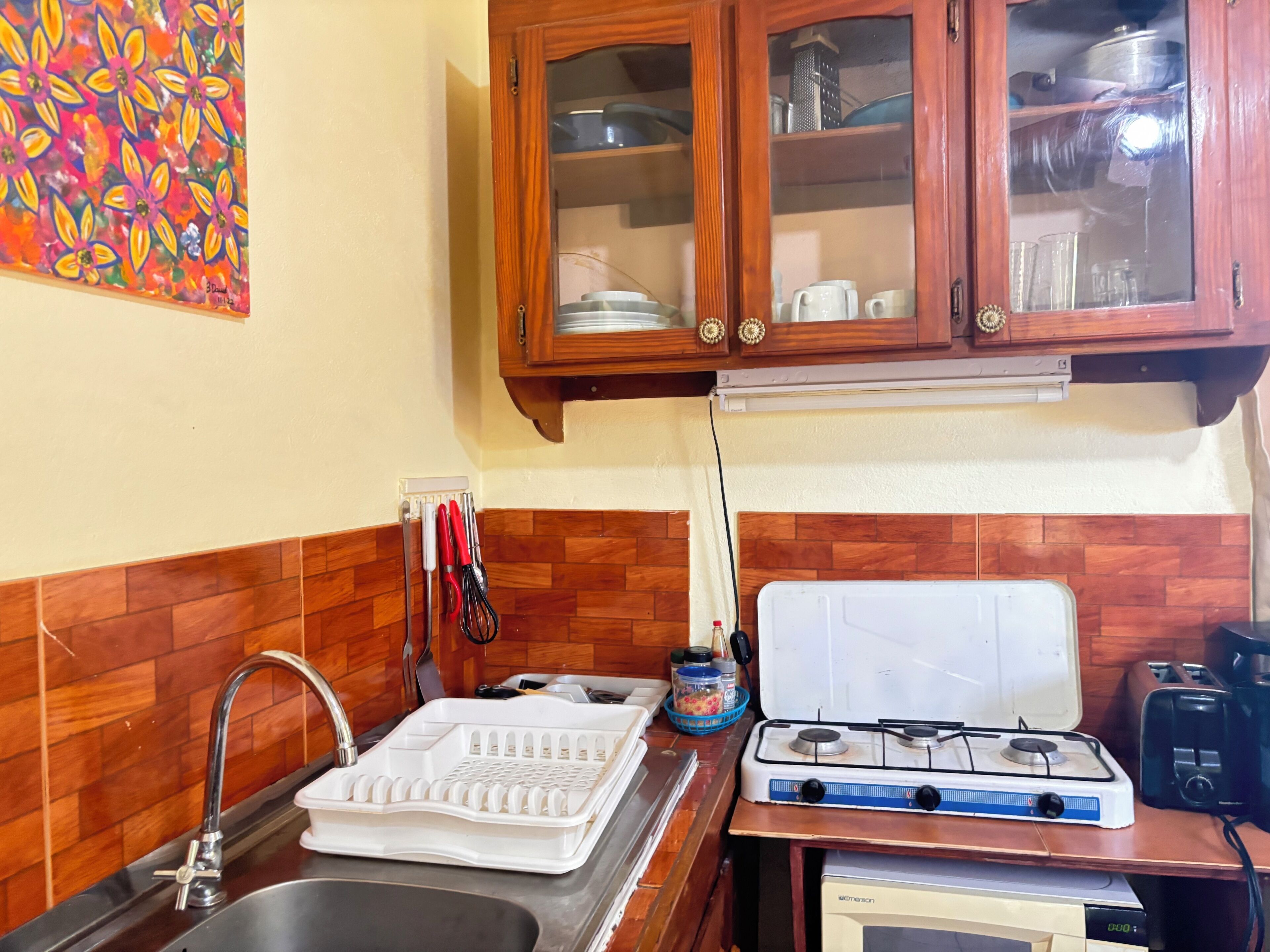 A kitchen with a sink, a stove, and wooden cabinets.