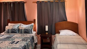 A bedroom with two beds, a ceiling fan, and a nightstand with a lamp. - Ellen Bay Cottages (Seatons Village)