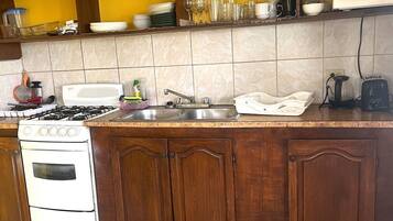 Een keuken met een fornuis, spoelbak en houten kastjes.