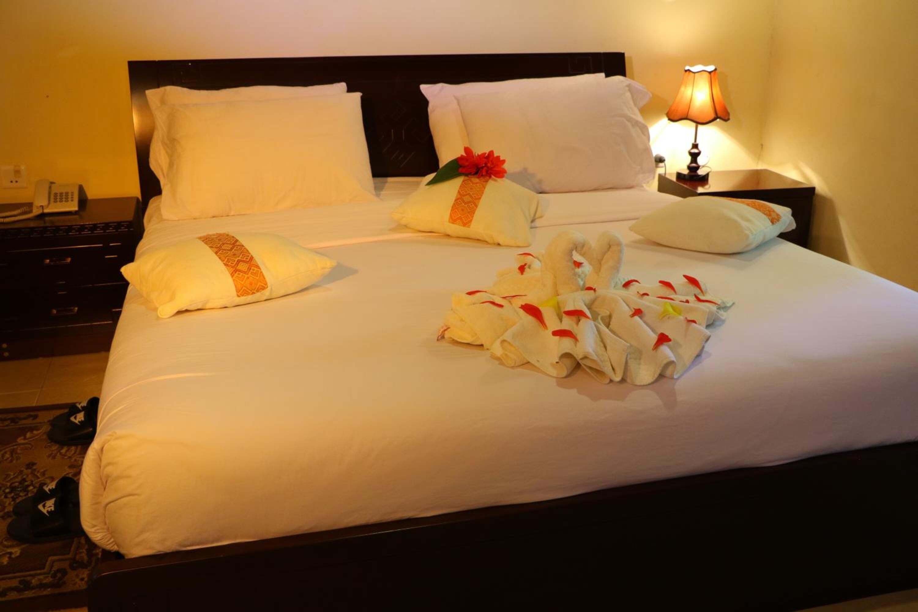 A neatly made bed with white linens, pillows, and a decorative towel arrangement.
