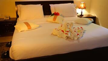 A neatly made bed with white linens, pillows, and a decorative towel arrangement.