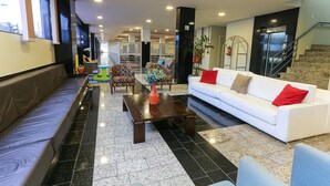 A modern lobby with a white sofa, a wooden coffee table, and a seating area with patterned chairs. - Hotel Express Rodoviária (Porto Alegre)