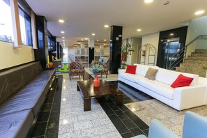 A modern lobby with a white sofa, a wooden coffee table, and a seating area with patterned chairs. - Hotel Express Rodoviária (Porto Alegre)