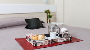 A neatly arranged breakfast tray on a bed with a coffee maker, a cup, and pastries. - Hotel Express Rodovi ária (Porto Alegre)