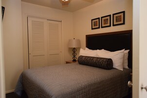 A bedroom with a bed, a nightstand, a lamp, and a door.