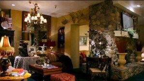 A cozy living room with a fireplace, a chandelier, and a stone wall.