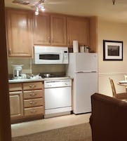 Una cocina con armarios de madera, un microondas blanco, un refrigerador y un lavavajillas.