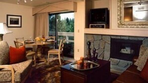 A cozy living room with a fireplace, a television, and a dining area with chairs and a table.