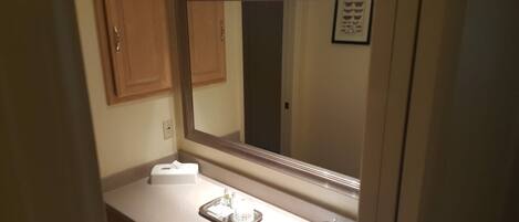 A bathroom with a large mirror, a sink, and a towel dispenser.