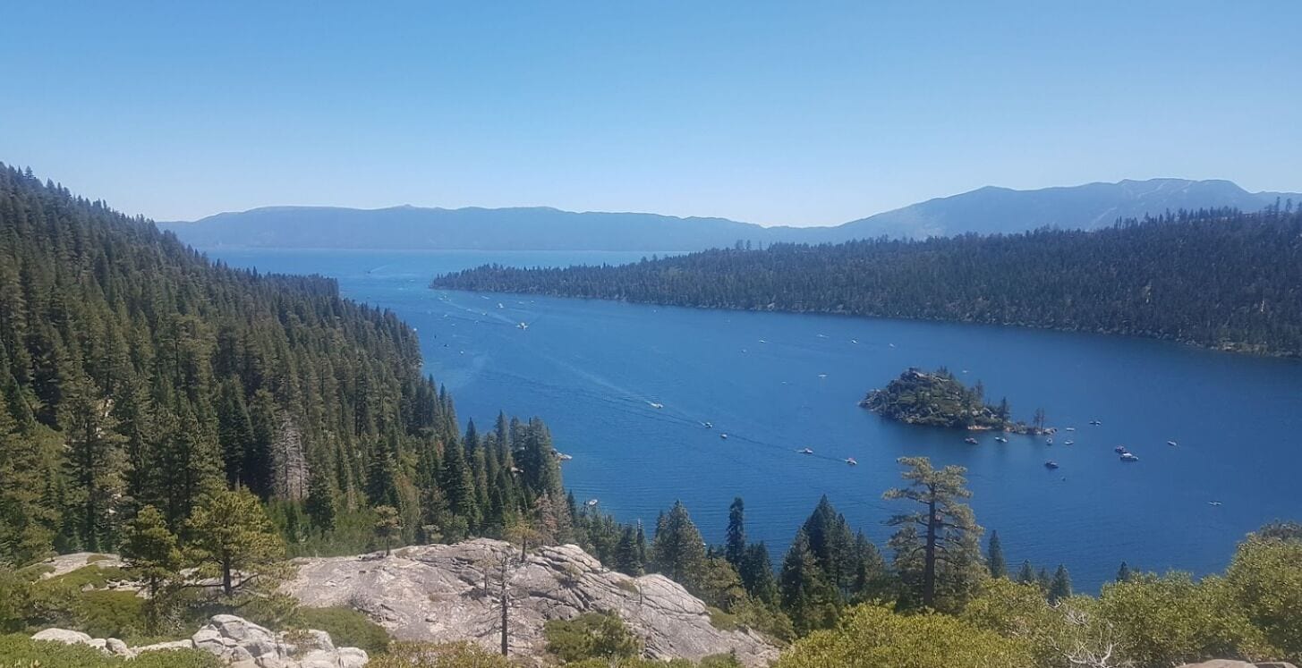 Vista panorámica de un lago rodeado de bosques densos y montañas.