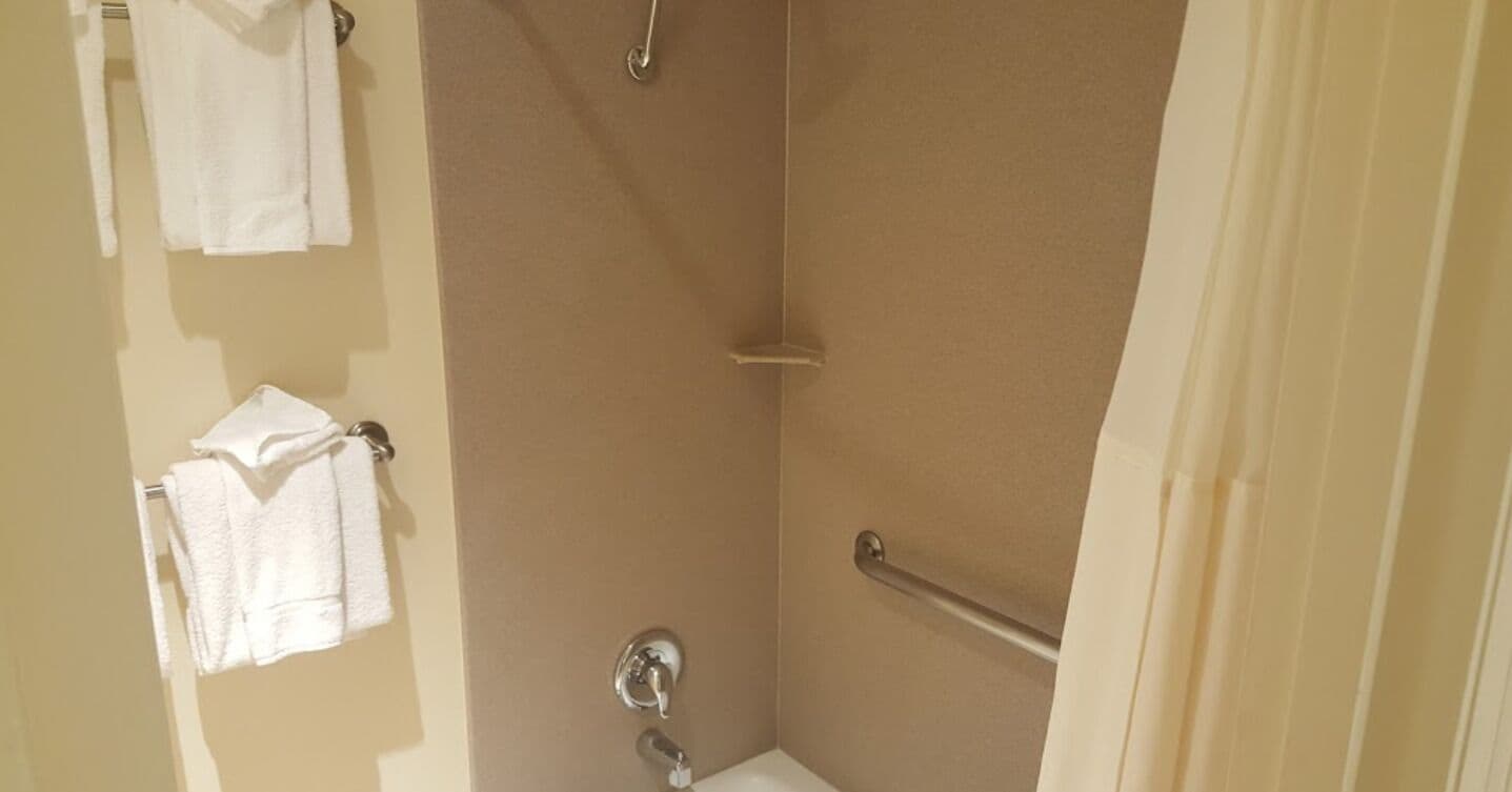 Un baño con ducha, inodoro y toallero con toallas.