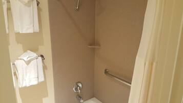 Un baño con ducha, inodoro y toallero con toallas.