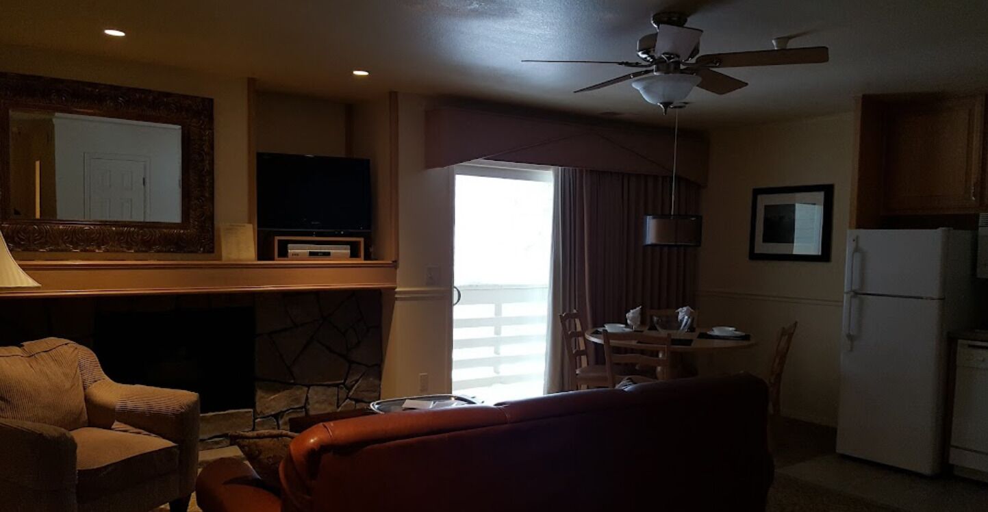 A living room with a fireplace, a television, a dining area, and a kitchen.