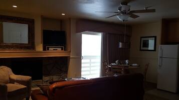A living room with a fireplace, a television, a dining area, and a kitchen.