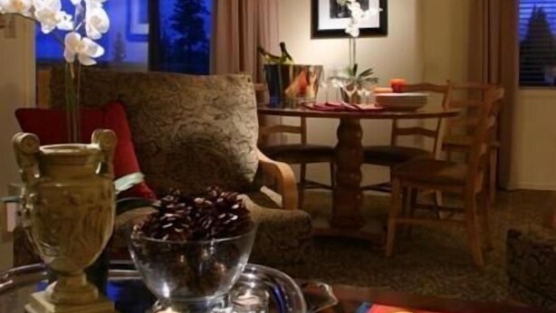 A dining area with a table set for two, featuring a book titled 'Picasso Postes' and a vase with white flowers.