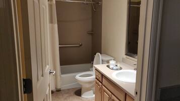 A bathroom with a bathtub, toilet, and vanity with a sink and mirror.