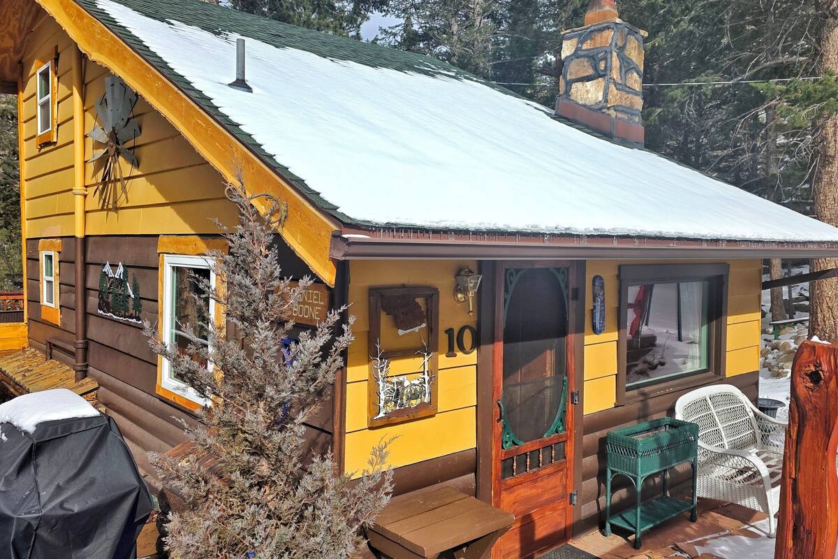 A yellow cabin with a number 10 sign, wooden exterior, and a porch with a bench and chairs.