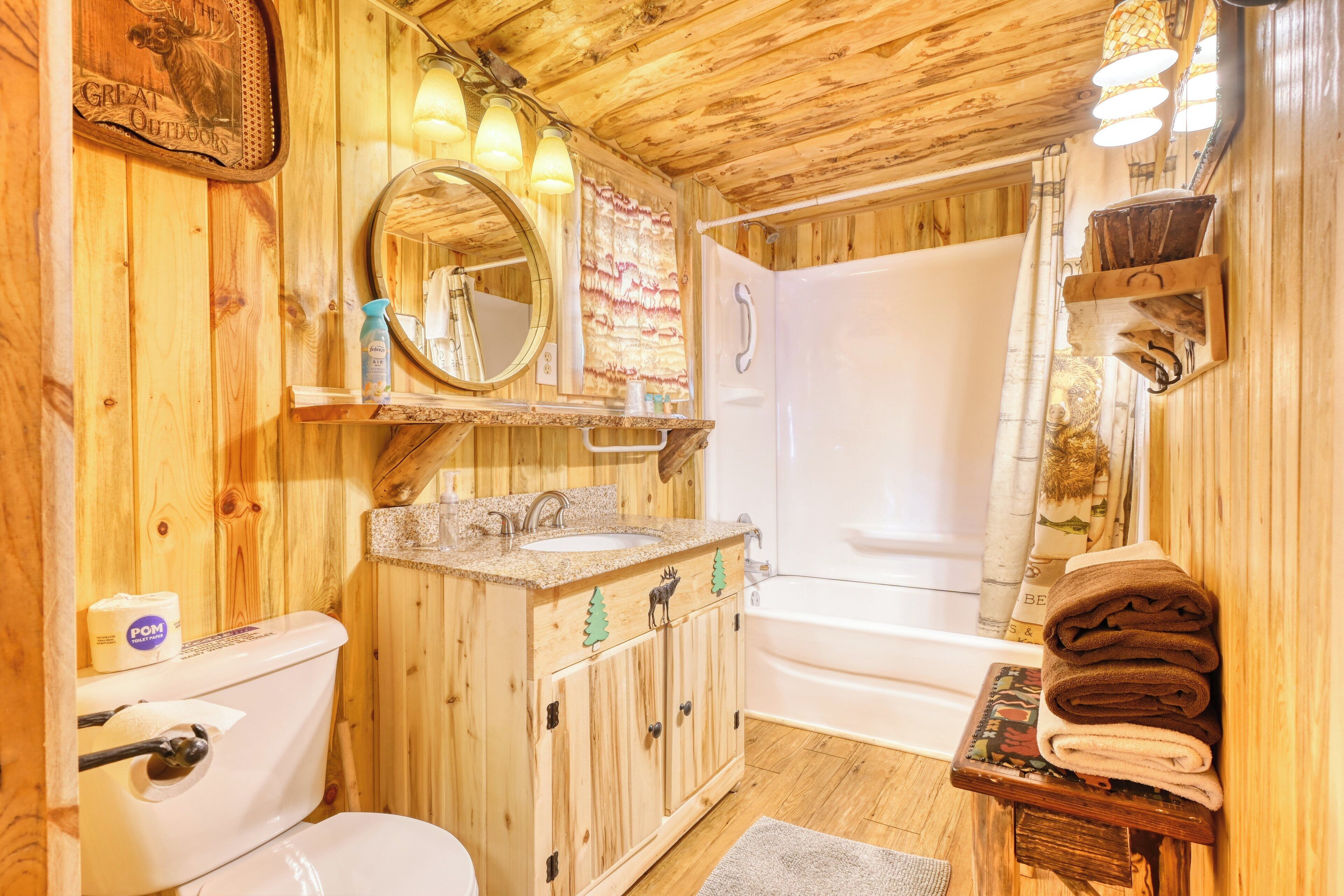 A wooden cabin bathroom with a toilet, sink, mirror, and bathtub.