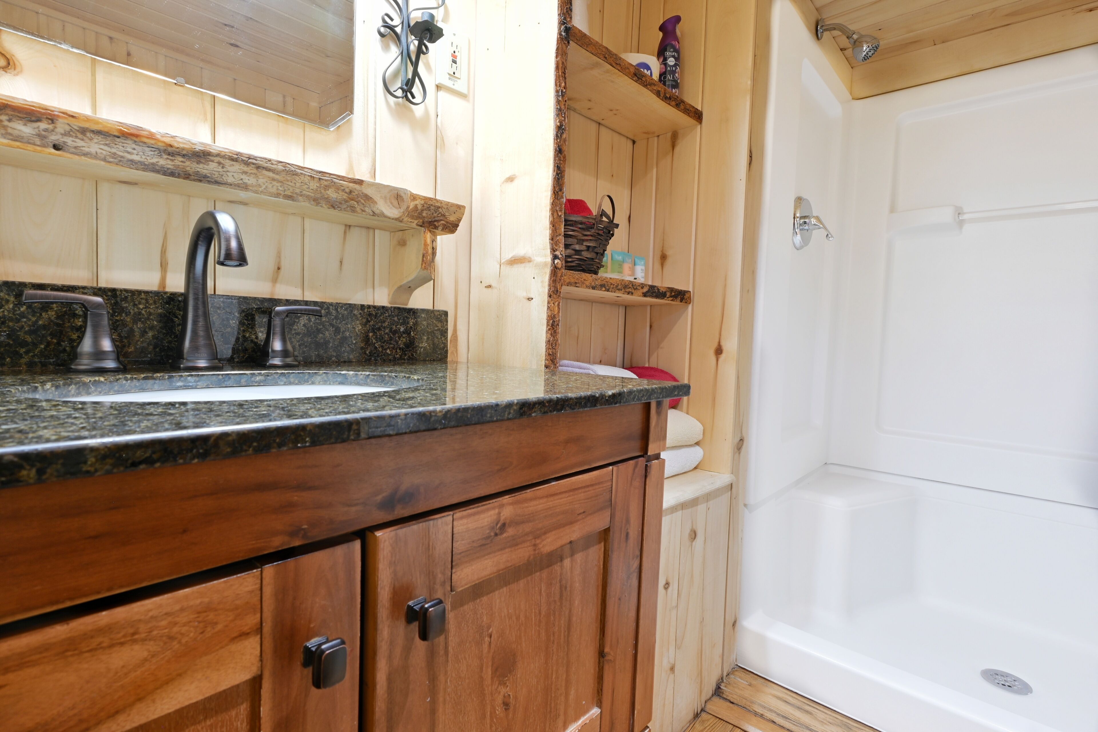 A wooden cabin-style bathroom with a granite countertop, a sink, and a shower.