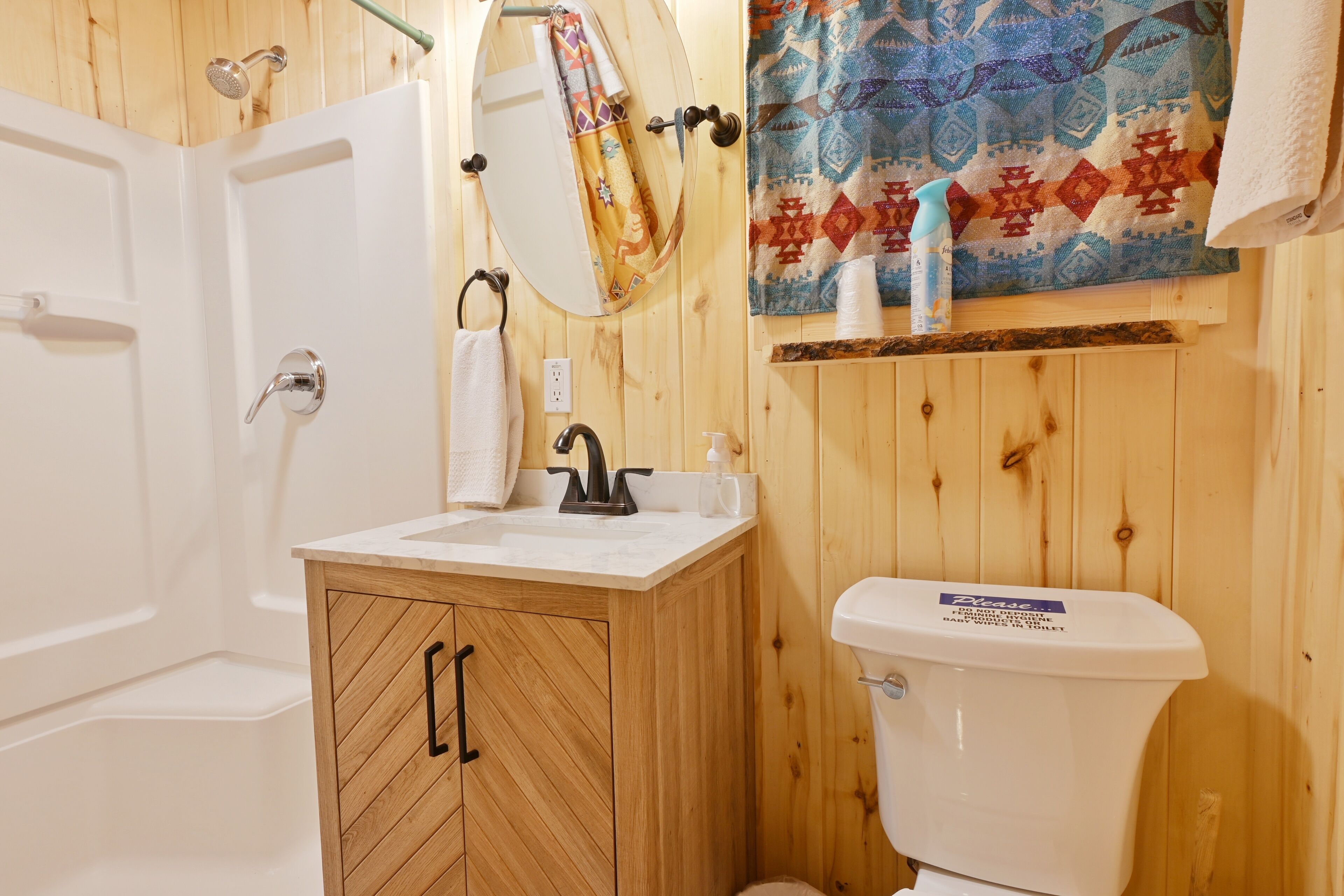 A bathroom with a wooden vanity, a toilet, a shower, and a towel hanging on the wall.