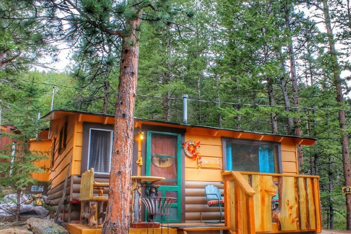 A rustic cabin with a wooden deck, a porch, and a dining area.