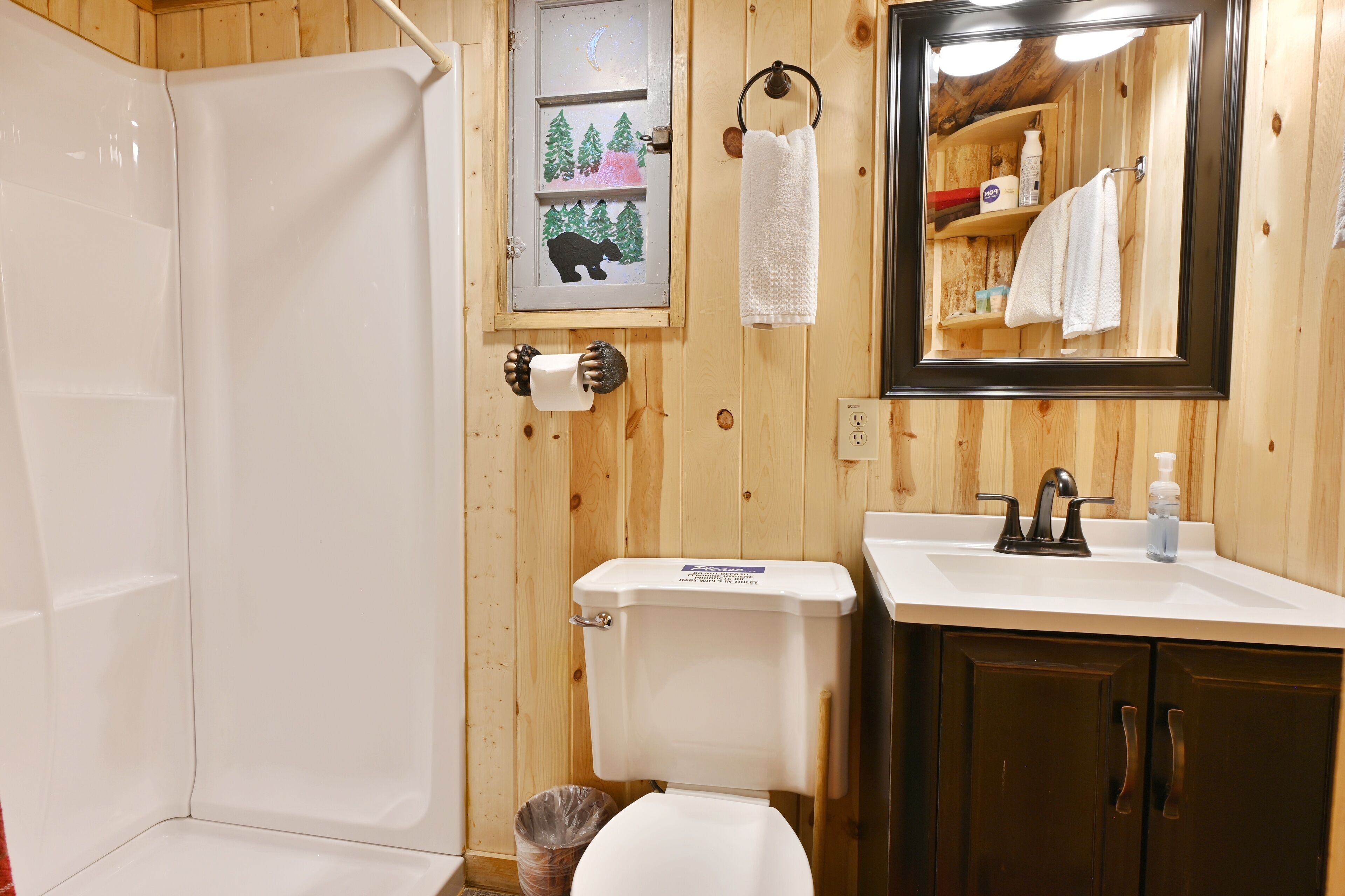 A bathroom with a shower, toilet, sink, and a mirror.