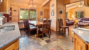 Interior de una cabaña de madera con comedor, cocina y sala de estar.