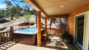 Una terraza de madera con un jacuzzi, un banco y una planta en maceta.