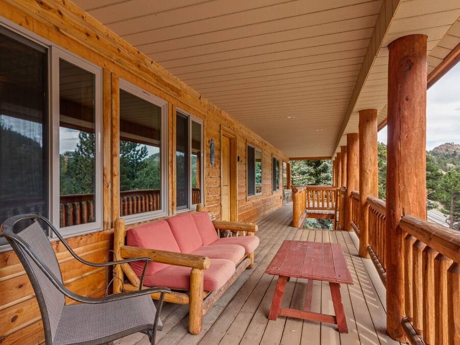 A wooden cabin with a porch, a sofa, a chair, and a table.