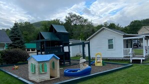 Un parque infantil con un tobogán, una casita y un complejo de juegos.