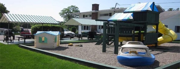 Un parque infantil con un tobogán, una casita y una estructura de juego con forma de barco.