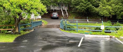 En belagt sti der fører hen til en bygning med en veranda, omgivet af frodig vegetation.
