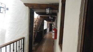 A corridor with a tiled floor, a metal railing, and a fire extinguisher mounted on the wall.