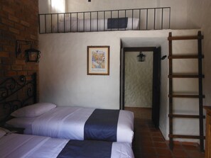 A bedroom with two beds, a wooden ladder, a map on the wall, and a brick wall. - Casa Indigo Hotel (San Cristóbal de las Casas)