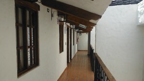 A corridor with white walls, tiled floor, and wooden railings.
