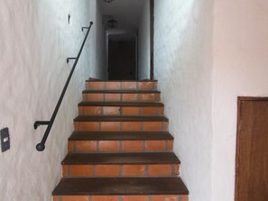 A staircase with brick steps and black handrails leading to a dark doorway. - Casa Indigo Hotel (San Cristóbal de las Casas)