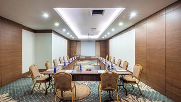 A conference room with a long table, chairs, and a projector screen.